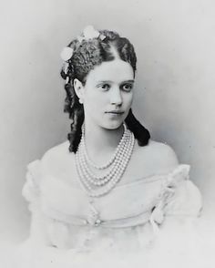 an old black and white photo of a woman with pearls in her hair wearing a dress