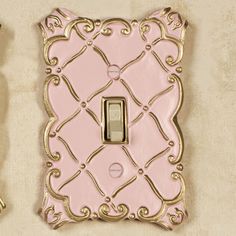 a pink and gold light switch cover sitting on top of a white wall next to a pair of scissors