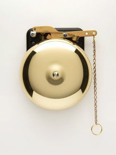 an overhead view of a golden bell on a white wall with a chain hanging from it