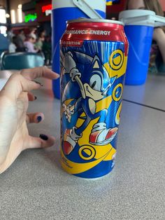 a can of sonic the hedgehog soda sitting on a table next to a woman's hand