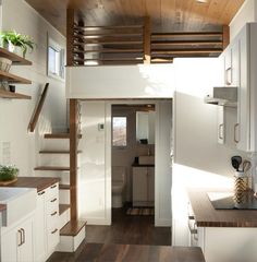 a kitchen and stairs in a tiny home with wood flooring, white cabinets, and open shelves