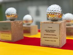 three golf balls sitting on top of a wooden block with a plaque in front of them