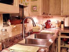 a stainless steel sink in a kitchen with lots of clutter on the counter top