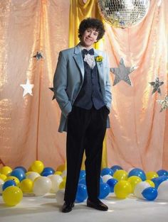 a man in a tuxedo standing next to balloons