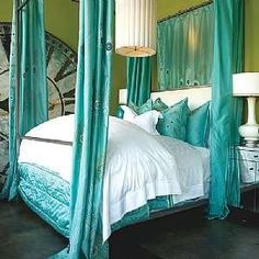 a green bedroom with four poster bed and white linens on the headboard, along with two lamps