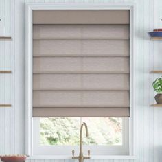 a kitchen window with roman shades in it