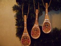 three wooden spoons decorated with ginger faces hanging from a christmas tree ornament