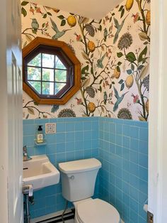 a blue tiled bathroom with a mirror and sink in the corner, next to a toilet