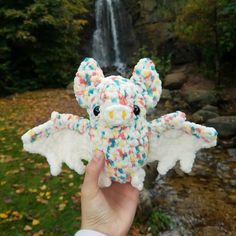 someone is holding up a stuffed animal with sprinkles in front of a waterfall