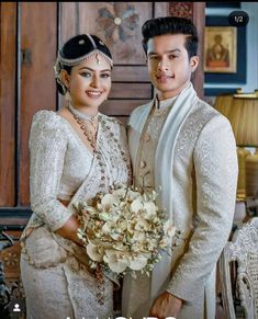 a man and woman standing next to each other in front of a wooden door holding flowers