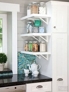 a kitchen with white shelves and black counter tops