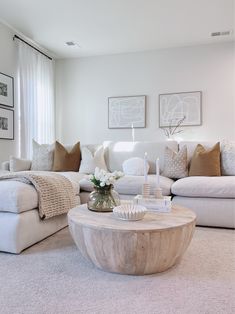 a living room filled with white furniture and lots of pillows on top of it's couches