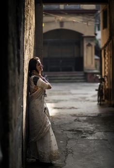 a woman leaning against a wall in an alley