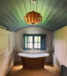 an old fashioned bathtub is in the middle of a room with wood paneling