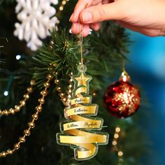 a hand is holding a ribbon ornament on a christmas tree