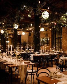 tables and chairs are set up for an event with lights hanging from the ceiling above them