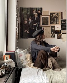 a woman sitting on top of a bed next to a wall covered in pictures and posters