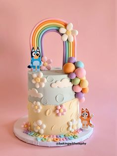 a birthday cake decorated with an image of a cat on the top and rainbow decorations