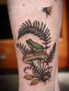 a green frog sitting on top of a mushroom with leaves around it and a bee flying by