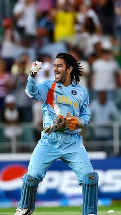 a man with long hair is standing on the field and holding his arms in the air