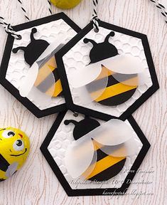 three bee shaped tags sitting on top of a table next to an orange and black ball