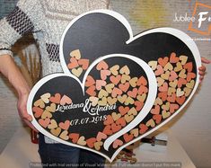 a person holding two heart shaped signs in front of a sign with hearts on it