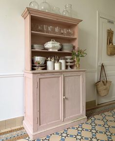 a pink hutch with dishes and cups on it