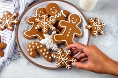 a plate full of ginger cookies with frosting on it and someone holding the cookie