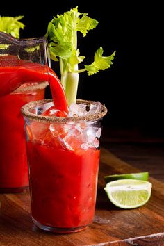 two glasses filled with red liquid and garnished with cilantro on the side