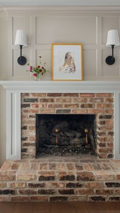 a brick fireplace in a living room with two lamps on either side