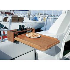 a plate of cookies and glasses on a wooden tray next to a boat in the water