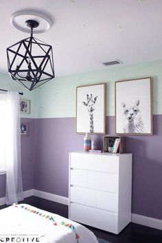 a bedroom with purple walls and pictures on the wall, including a white chest of drawers