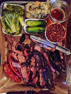 a tray with meat, vegetables and sauces on top of it next to a fork