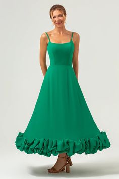 a woman wearing a green dress with ruffles on the bottom and straps at the waist