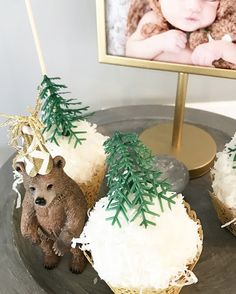 two cupcakes with white frosting and green trees on top are sitting on a plate