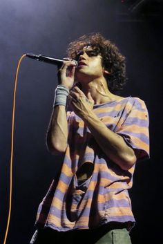 a young man singing into a microphone on stage