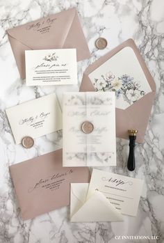 the wedding stationery is laid out on a marble table