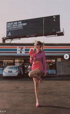 a woman is dancing in front of a gas station with her legs spread out to the side