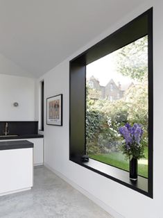 a kitchen with an open window and white cabinets, black counter tops, and marble flooring