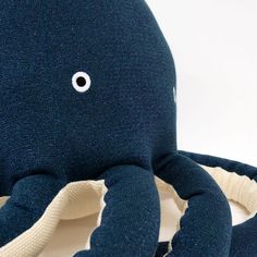 an octopus stuffed animal sitting on top of a white table next to a blue pillow