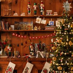 a christmas tree in front of a fireplace with stockings hanging from it's sides