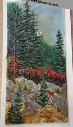 a painting of some trees and rocks in the woods with snow on their leaves is hanging on a wall