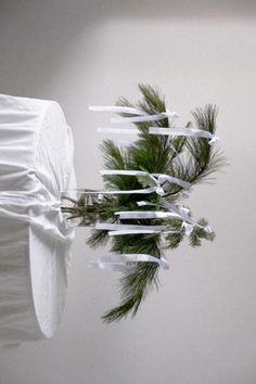 an arrangement of pine branches and ribbons tied to a white sheeted bed with sheets on it