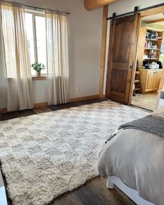 a bed room with a neatly made bed and a large rug in front of a window