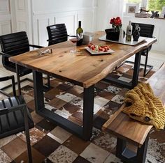 a wooden table sitting on top of a brown and white checkered floor next to two black chairs