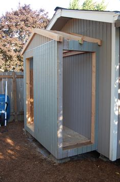 a small shed with the door open and some wood on the ground next to it