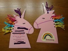 two paper unicorns with rainbow manes on them