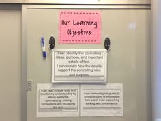 a bulletin board with writing on it and two sticky notes attached to the wall behind it