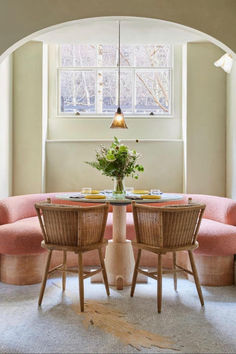 a dining room table with chairs and a bench in front of it, under an arched window