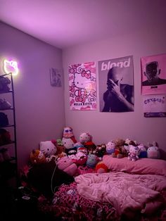 a bed with pink sheets and stuffed animals on it in a room that has posters above the bed